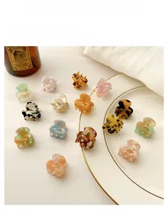 Flat lay of mini acetate claw clips with amber and marble patterns on a white marble surface