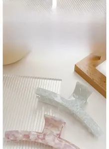 Dettaglio di mollette per capelli in acetato con motivi tartarugati e fiori viola