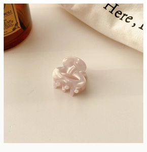 Detail of a mini acetate hair claw clip with pink marble texture and pearlescent finish