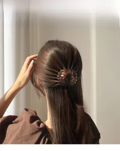 Detailed back view of a resin bird nest hair clip securing a brown leopard print ponytail