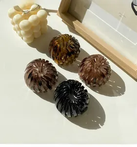 Detailed view of bird nest hair clips in black, amber, and brown on a minimalist background