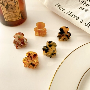Set of 5 mini acetate hair claws in tortoiseshell and marble patterns on white surface