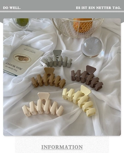 Matte finish wavy claw clips in neutral tones displayed on elegant white silk fabric