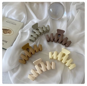 Macro view of matte wavy hair claws in Morandi colors displayed on white silk