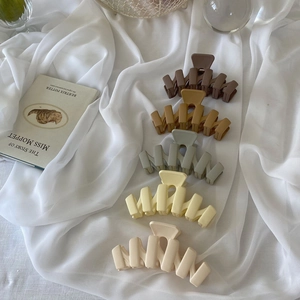 Five matte wavy hair claws in brown, cream, and green shades displayed on a white cloth