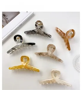 Detailed close-up of six marble and amber textured acrylic hair claws on white background