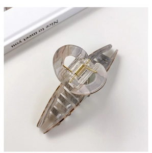 Macro view of a large marble texture hair claw clip with a strong gold metal spring