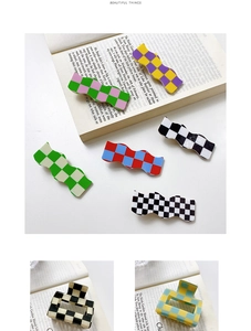 Close-up of assorted checkered acrylic hair clips and claws on minimalist book background