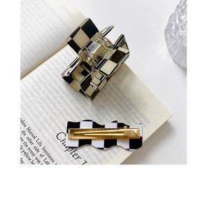 Detailed view of checkered square hair claw and wave clip on an open vintage book