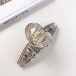Elegant acrylic claw clip with grey marble texture and gold metal spring on white background