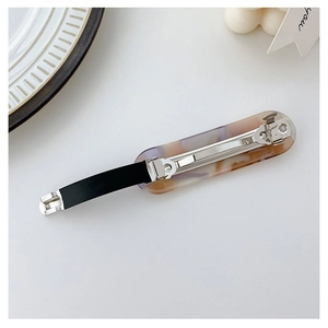 Detail view of the metal spring clip back and marble texture acrylic hair barrette