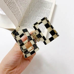 Classic black and white checkered rectangle hair claw clip on a vintage book background