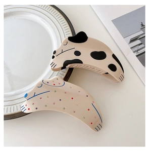 Close-up of cute dog-shaped acetate hair claws in cow print and colorful polka dots