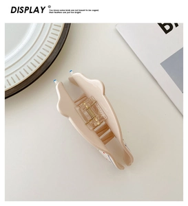 Close-up of a milk tea colored acetate dog-shaped hair claw with blue and red dot accents