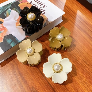 Elegante Blumen-Haarklammern mit Perlenverzierung in vier Farben auf einem Kunstbuch