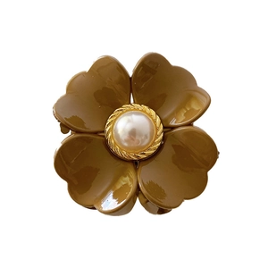 Braune Blumen-Haarklammer mit Perle und goldenen Metallrändern auf weißem Hintergrund