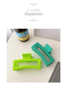 Close-up of two large matte green rectangle hair claw clips for women hair styling