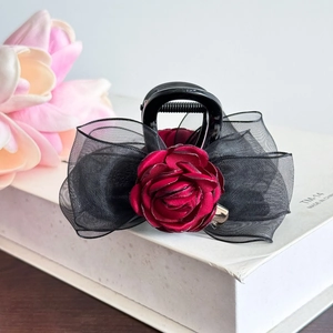 Détail de la grande pince à cheveux avec rose en tissu rouge foncé et nœud en organza noir