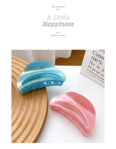 Close-up of pastel blue and purple jelly texture hair claws with gold logo on wood tray