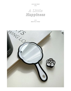 Elegant handheld makeup mirror with black and white camellia motif and matching accessory
