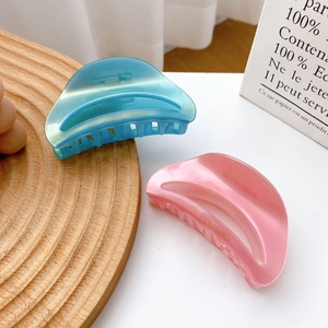 Polished acetate half-moon hair claws in soft pink and blue with gold branding
