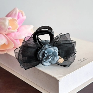 Détail d'une pince à cheveux élégante avec nœud en résille noire et fleur de camélia