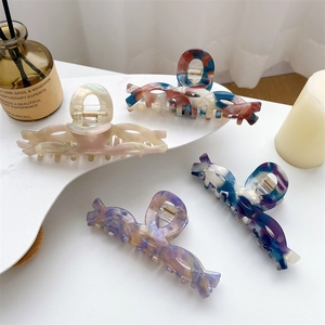 Elegant large acetate hair claws in four colors for women displayed on white stand