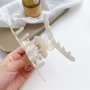 Large vintage acetic acid hair claw clip in iridescent white shown in hand
