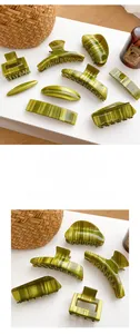 Detailed view of olive green acetate hair clips with marble texture on a woven basket