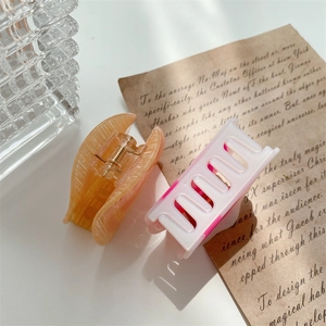 Elegant acetic acid hair claws in amber orange and pink white gradient on a white desk