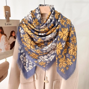 Elegant 130cm square scarf with blue and yellow floral prints on a beige wool coat