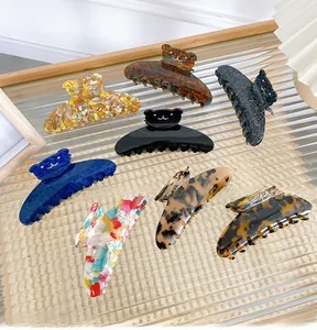 Detailed close-up of rhinestone bear hair clips in various patterns on glass surface
