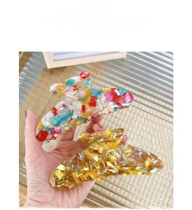Close-up of a large floral acetate hair claw clip with colorful marble patterns