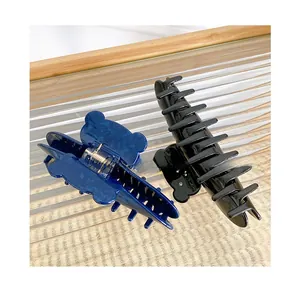 Close-up of two large rhinestone bear hair claws in translucent blue and glossy black finish