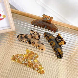Elegant rhinestone bear hair claws in assorted acetate finishes on a glass tray