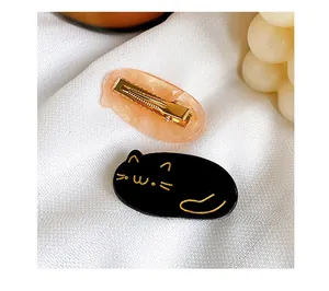 Close-up of cute cat motif duckbill hair clips with pink resin and black finishes