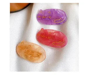Macro shot of glittery acrylic cat-shaped hair clips in purple, pink and amber marble tones
