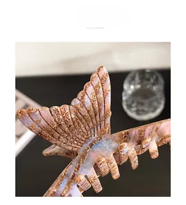 Macro detail of large acetate claw clip with iridescent fishtail and marble patterns