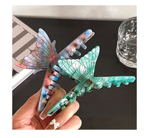 Close-up of butterfly claw clips in blue-pink marble and emerald green patterns
