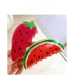 Detailed view of acrylic hair claws in strawberry and watermelon fruit shaped designs