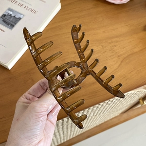 Elegant large amber brown hair claw clip held over a warm rustic home decor setting