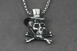 Macro view of punk skull pendant with top hat and crossbones on silver box chain