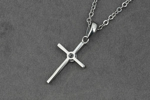 Gros plan détaillé d'un collier pendentif croix en argent avec un petit diamant central