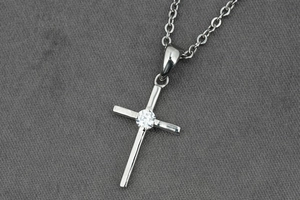 Détail d'un pendentif croix argenté avec pierre de zircone et chaîne à maillons fins