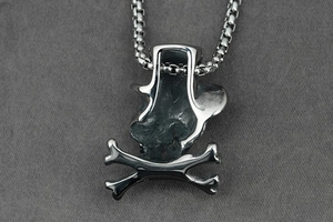 Detailed macro view of punk style skull pendant with box chain on grey fabric
