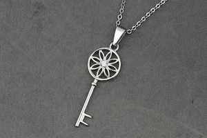 Vue détaillée d'un pendentif clé en argent avec découpe florale et cristal étincelant