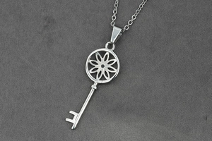 Vue détaillée du collier avec pendentif en forme de clé argentée au motif floral ajouré