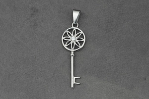 Détail d'un pendentif clé en argent avec motif floral évidé et cristal central brillant