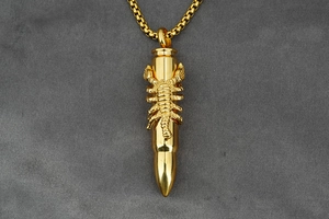 Macro shot of gold bullet pendant with a detailed 3D scorpion relief on a square link chain