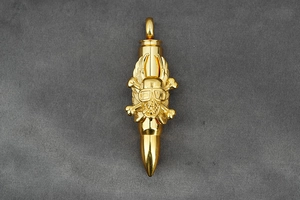 Detailed macro view of golden bullet pendant featuring skull and wings punk design